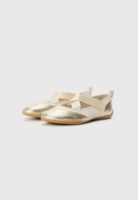 Ballerine oro e crema con design a fascia incrociata, texture trapuntata e suola in gomma. Tessuto morbido e lucentezza sottile.