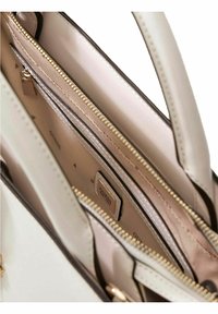 Borsa beige chiaro con molteplici scomparti con cerniera, texture liscia, dettagli metallici dorati e un'etichetta con logo prominente all'interno.