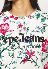 Biały sweter z wyrazistym kwiatowym nadrukiem w kolorach czerwonym, niebieskim i zielonym. Posiada wyraźne czarne hafty z napisem "Pepe Jeans" oraz tekstem "LONDON IN BLOOM".
