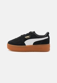 Sneakers din suede negre cu o dunga albă PUMA, având o talpă din cauciuc de tip gumă și un design minimalistic. Accentele logo-ului aurii se află pe limbă.