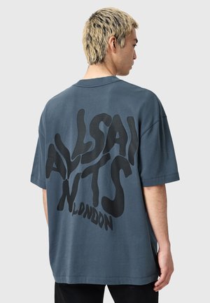 Overdimensioneret navyblå bomuldst-shirt med et dristigt sort tekstgrafik på ryggen. Korte ærmer og rund halsudskæring.