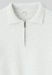 Pull-over gris clair avec fermeture éclair mi-longue, col et texture douce. L'étiquette indique "B2B LOOSE" avec la taille "L".