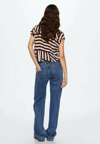 Brown and cream striped short-sleeve top paired with blue wide-leg jeans, showing back view, with visible pockets and casual fit.