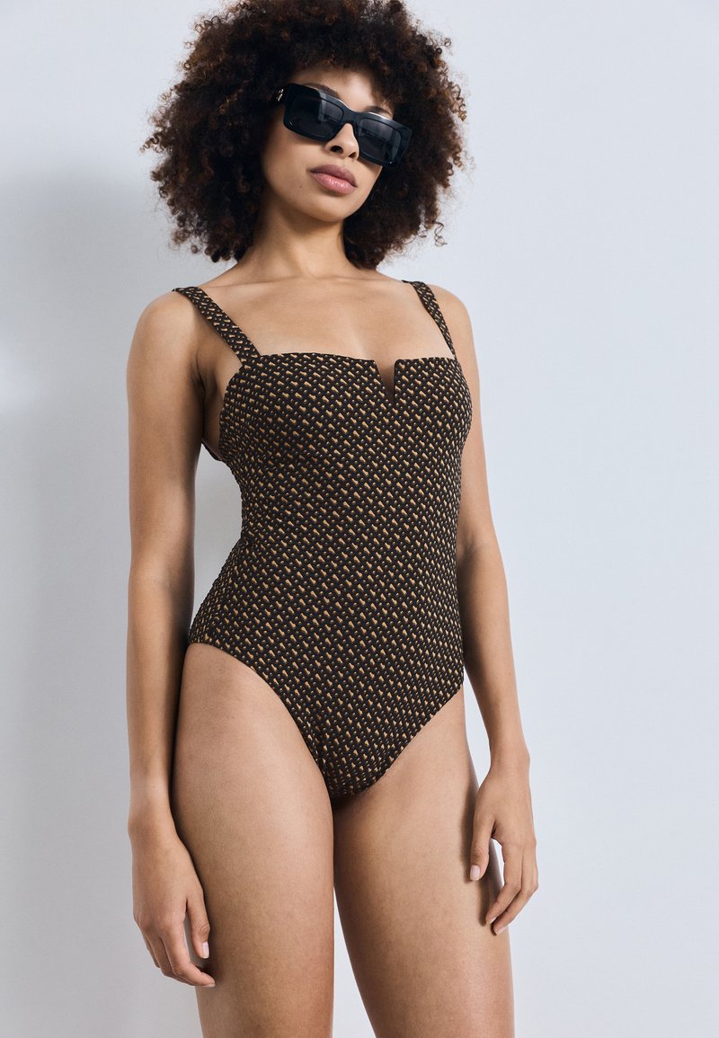 Brunmønstret heldraktbadebukse med dyp utringning, tykke stropper og høyt skjærte ben. Har et teksturert stoffdesign.