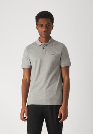 Grau Polohemd aus weichem Stoff, mit Kragen, zwei Knöpfen und einem kleinen Logo-Patch auf der linken Brust. Kurze Ärmel.