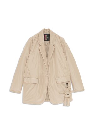 Beige gepolsterte Blazer mit Reverskragen, zwei vorderen Taschen, Knopfverschluss und einem abnehmbaren Plüsch-Anhänger an der Seite. Glatte Textur.