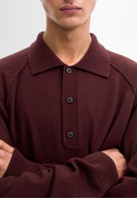 Bordeaux gebreid poloshirt met een kraag, vier zwarte knopen en geribbelde manchetten; beschikt over een zachte textuur en subtiele stikdetails.