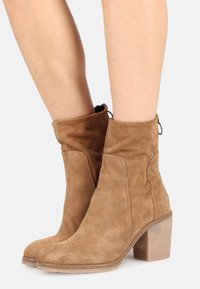 Bottines en daim marron avec un embout arrondi, une tige décontractée et un talon carré texturé. Dotées de détails de couture et d'une languette à l'arrière.