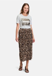 Jasnoszara koszulka z lampartowym wzorem i napisem, połączona z długą plisowaną spódnicą w czarno-beżowy wzór zwierzęcy.