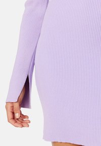 Abito lavanda a coste con maniche lunghe, caratterizzato da spacchi laterali all'orlo e una silhouette aderente. Texture morbida con una finitura pulita.