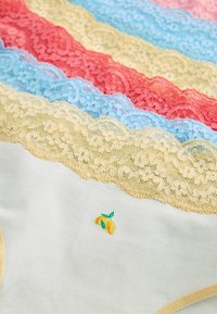 Couches de tissu blanc et pastel bordées de dentelle avec un petit motif de citron sur un fond textile blanc doux.