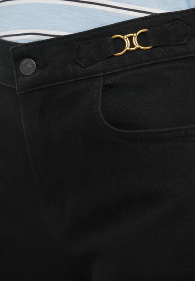 Musta denim-housut, joissa on sileä tekstuuri, klassinen leikkaus ja kullanvärinen metalliosa vyötäröllä sulkemista varten.