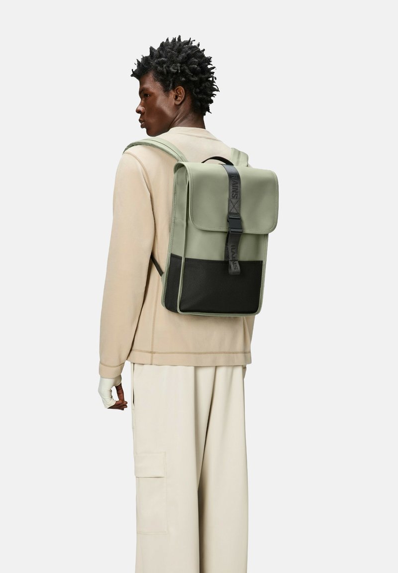 Mochila verde y negra con cierre de solapa, correas ajustables y un diseño elegante. Fabricada con materiales suaves y una forma estructurada.