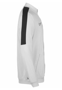 Nike-Jacke, leichtes Material, weiß mit schwarzen Seitenpanelen. Verfügt über einen Stehkragen, einen durchgehenden Reißverschluss und zwei Seitentaschen.