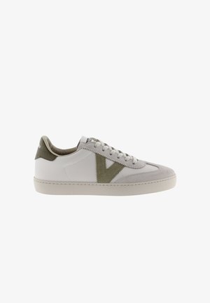 Zapatilla blanca con acentos de ante verde oliva, que presenta una puntera texturizada, diseño de cordones y una suela plana de goma. Forma simple y geométrica.