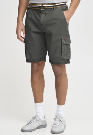 Dark green cargo shorts with rolled hems, side pockets, and a contrasting striped belt. Worn with gray athletic shoes and white socks.