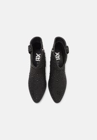 Botas de tobillo negras con punta afilada, que presentan adornos texturizados y cierre de cremallera. Confeccionadas en material suave con un acabado liso.