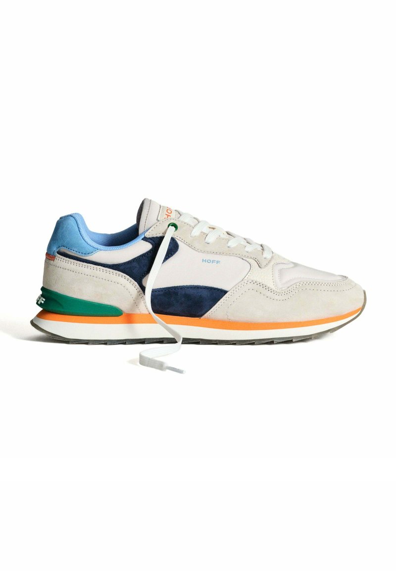 Baskets gris clair avec un mélange de cuir lisse et de suède, accents bleus, et détails verts et orange sur la semelle, accompagnées d'un lacet blanc.