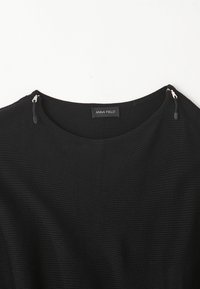 Czarny sweter prążkowany z okrągłym dekoltem, lekko teksturowany, z srebrnymi zamkami na ramionach. Metka głosi "ANNA FIELD."