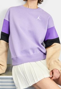 Sudadera púrpura con mangas en bloque de color en púrpura oscuro, negro y beige. Fabricada con una tela suave, cuenta con puños acanalados y un logo en el pecho.