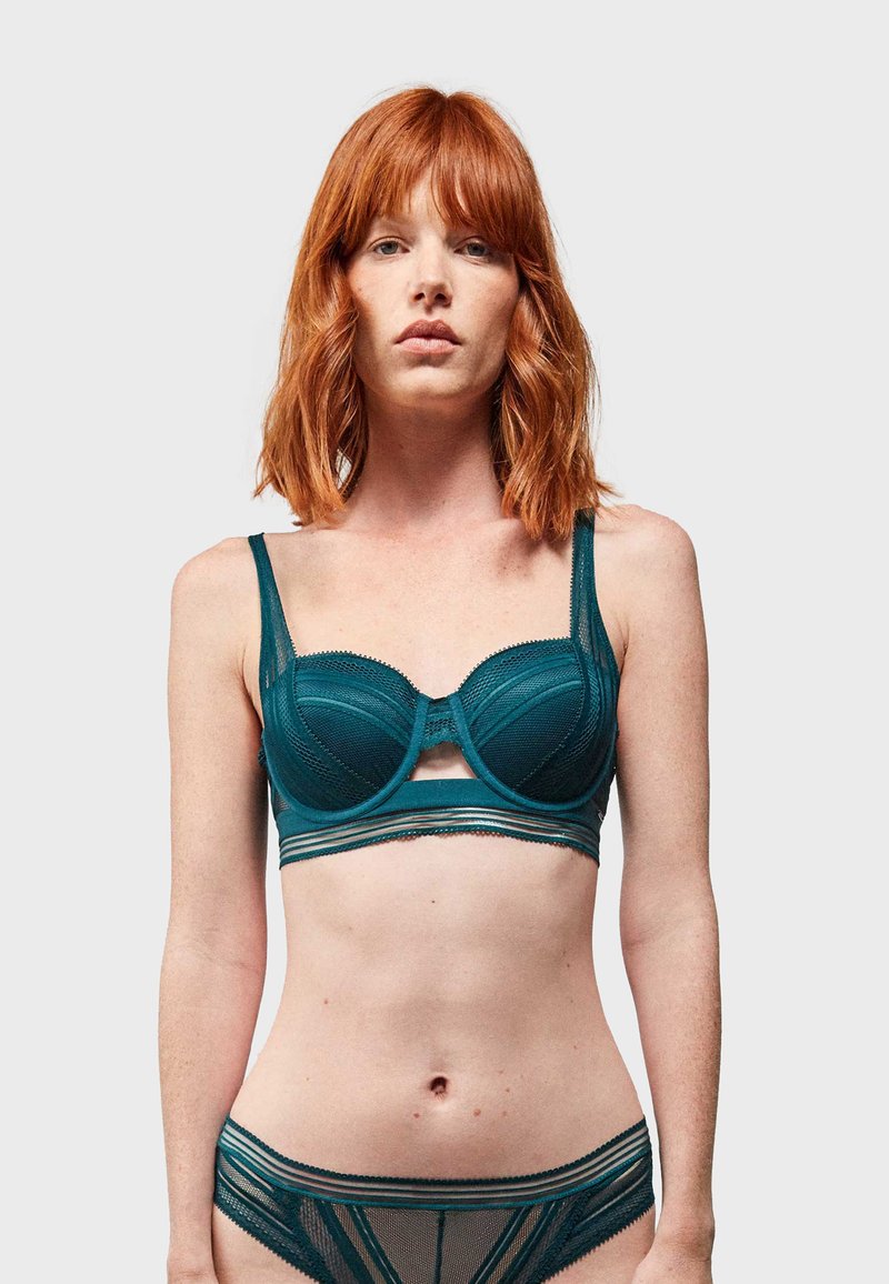 Reggiseno teal con ferretto. I pannelli in rete e satin creano un effetto a strati. Slip coordinati con motivo teal. Spalline regolabili.