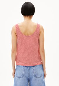 Red and white striped tank top with a wide scoop back; cotton material. Paired with high-waisted denim shorts featuring back pockets.