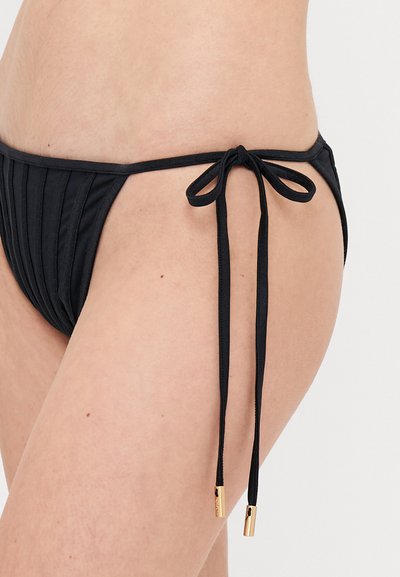 Melnas bikini apakšda ar pleto tekstūru, sānu saišu aizdari un zelta akcentiem uz auklu galiem. Izstrādāta, lai nodrošinātu pieguļošu izskatu.