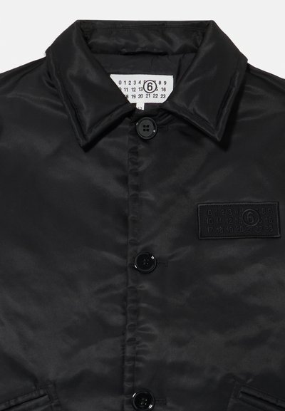 Schwarze Satinjacke mit Kragen, zwei Knöpfen auf der Vorderseite und einem strukturierten Patch mit Zahlen. Glatte Oberfläche mit minimalistischer Gestaltung.
