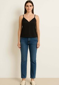 Camisola nera di satin con spalline sottili, dotata di scollo a V e dettagli in pizzo, abbinata a jeans aderenti azzurri e mocassini beige.