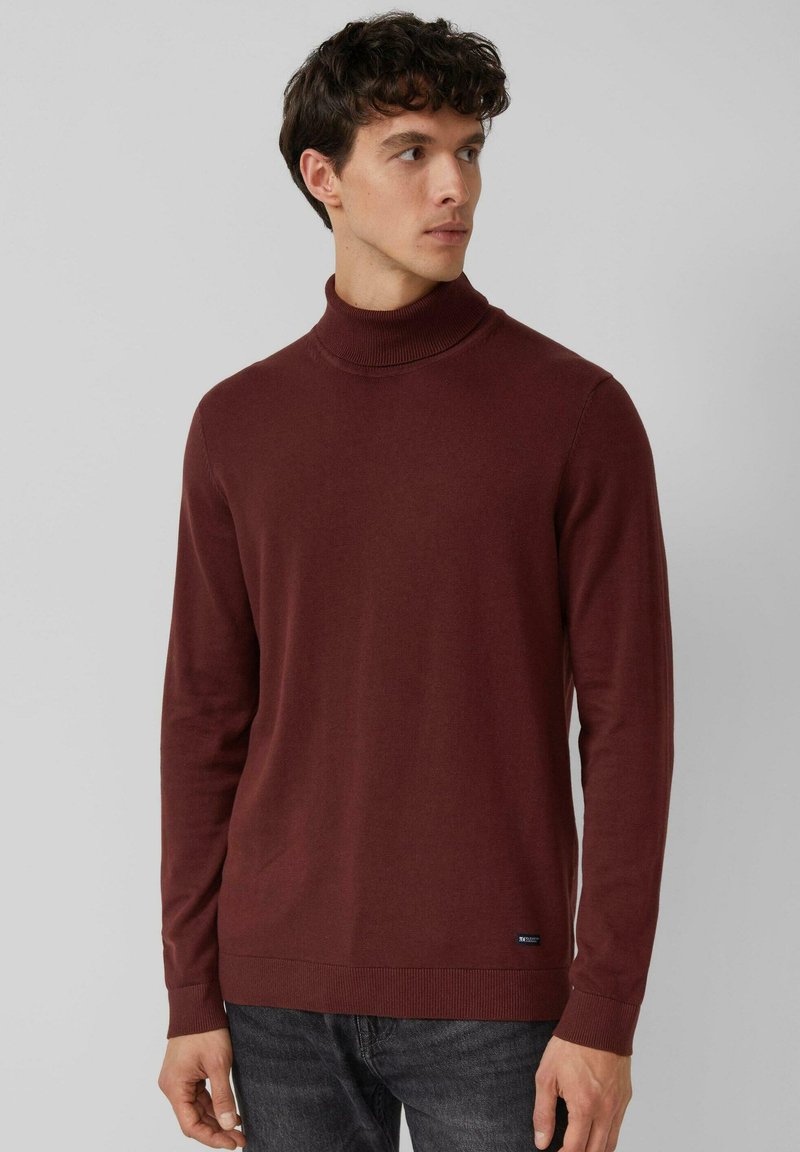Bordowy sweter z golfem wykonany z miękkiej dzianiny. Posiada długie rękawy, dopasowany kołnierz oraz małe logo przy dolnym brzegu.