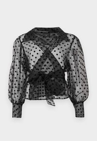 Blouse noire transparente à motifs à pois, taille ceinturée, longues manches bouffantes et col classique. Tissu léger avec une texture douce.