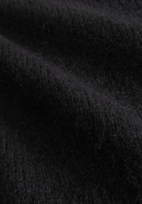 Fekete, texturált szövet lágy, bolyhos felülettel. Az anyag vastagnak tűnik, látható rostokkal és enyhe fényességgel.