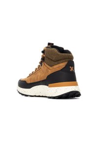 Zapato de senderismo alto en marrón y negro, con tejido texturizado, suela de goma y acentos en naranja. Presenta un cierre con cordones en la parte delantera y un cuello acolchado.