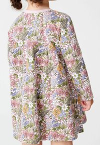 Floral dress featuring a pink background with a colorful pattern of various flowers and greenery. Long sleeves and round neckline.