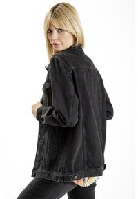 Czarna kurtka dżinsowa o luźnym kroju, z zapięciem na guziki i bocznymi kieszeniami. Charakteryzuje się wyraźnie teksturowanym materiałem i nieco przesadzonym fasonem.