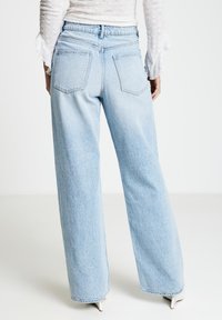 Jeans a gamba larga di colore azzurro chiaro realizzati in denim. Caratterizzati da vita alta, fascia elastica e due tasche posteriori con effetto slavato.