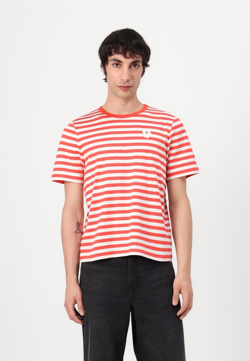 Tricou scurt cu mâneci, cu dungi roșii și albe, gât rotund și un detaliu grafic mic alb pe piept. Fabricat din material de bumbac.