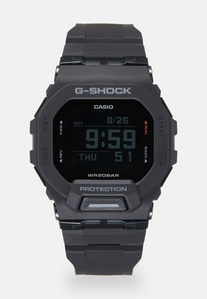 Reloj G-SHOCK con caja y correa de resina negra mate, pantalla digital y acentos naranjas. Incluye fecha, hora y resistencia al agua hasta 20 bares.