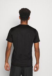 Svart kortärmad sporttröja med rundad hals, slät yta och minimal sömdetalj, sedd bakifrån.