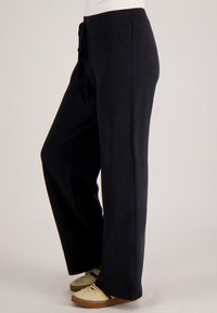 Zwarte, losvallende broek met een elastische tailleband en trekkoord. Gemaakt van zachte stof, met rechte pijpen en een comfortabele pasvorm.