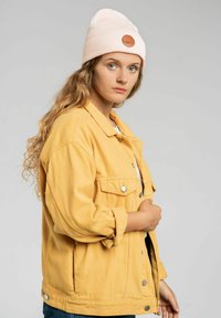 Żółta dżinsowa kurtka o luźnym kroju, z srebrnymi napami i dwiema kieszeniami na piersiach. W zestawie z jasnoróżową czapką beanie z logo.