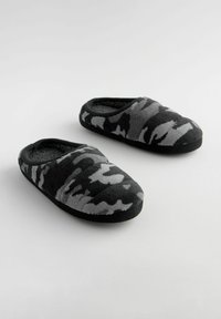 Chaussons à motif camouflage noir et gris, fabriqués en polaire douce, avec un bout rond, un design à enfiler et une semelle en caoutchouc texturé.