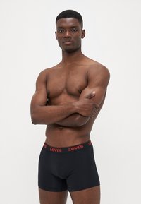 Schwarze Boxershorts mit einem roten Levi's-Logo am Bund. Hergestellt aus einem glatten Material, figurbetontes Design, mit einem klassischen Schnitt ohne Muster.