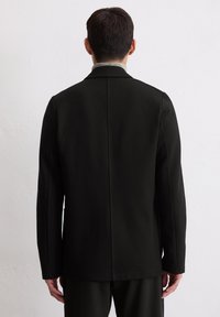 Schwarze Jacke mit geradem Schnitt und minimalistischem Design. Aus glattem Stoff gefertigt, mit einer Rückenschlitz und dezenten Schulternähten.