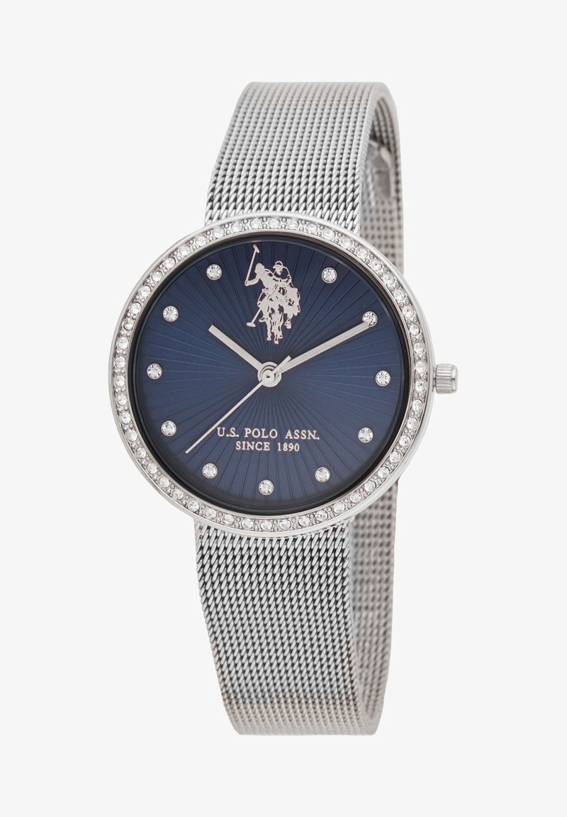 Orologio con cinturino in rete argentata e quadrante ovale blu, con indici delle ore argentati e una lunetta impreziosita da cristalli. Presenta il design del logo U.S. Polo Assn.