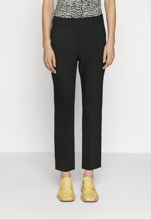 Sorte skræddersyede bukser med en slim fit og cropped længde, kombineret med gule mokkasinstil sko. Glat stof og minimale detaljer.