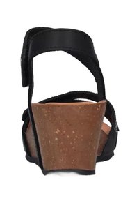 Sandal nera con tacco in sughero, dotata di cinturini regolabili e una parte posteriore texturizzata per una maggiore aderenza. Cuciture precise lungo i bordi dei cinturini.