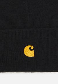 Black knitted beanie with a folded cuff featuring a small, embroidered yellow logo on the front. Material appears soft and textured.