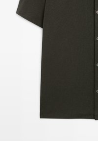 Short-sleeve dark green button-up shirt with a visible left sleeve and row of buttons on the right side.