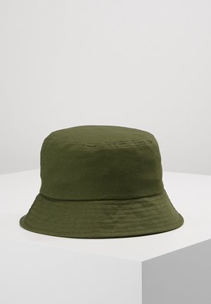 Chapeau bob en coton vert olive avec des détails cousus autour du bord, présenté sur une surface blanche sur fond gris.
